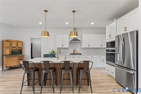 a kitchen with stainless steel appliances a dining table chairs refrigerator and microwave