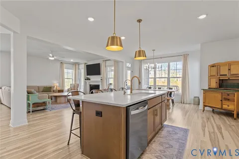 a view of a kitchen counter top space with sink wooden floor and living room view