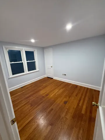 a view of empty room with wooden floor and windows