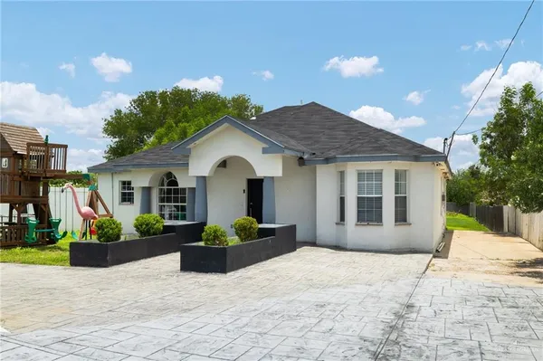 a front view of a house with a yard and potted plants