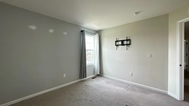 an empty room with a window and a refrigerator