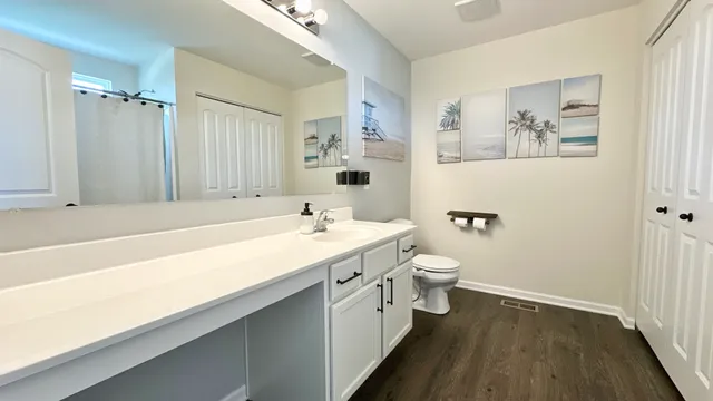 a spacious bathroom with a granite countertop sink a toilet a mirror and shower