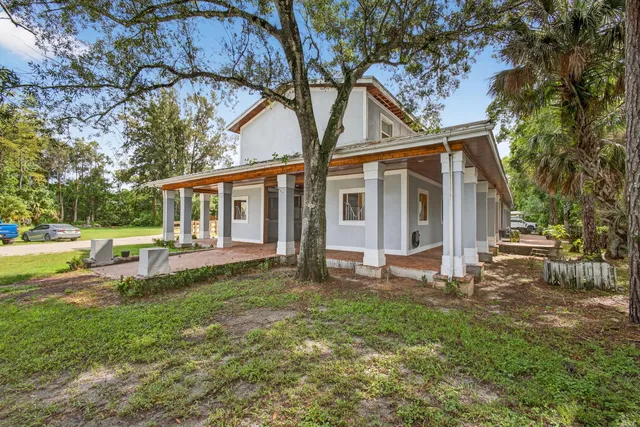 a view of a house with backyard and a tree