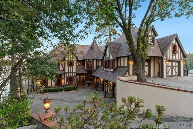 a front view of a house with a garden and tree