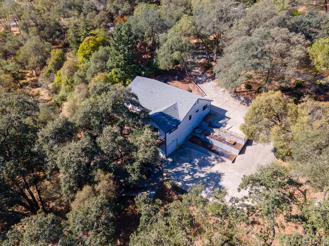 an aerial view of a house with a yard and large tree