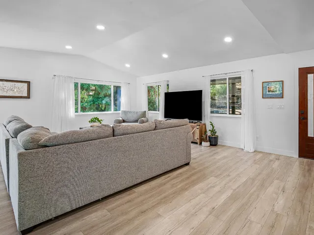 a living room with furniture kitchen and a wooden floor