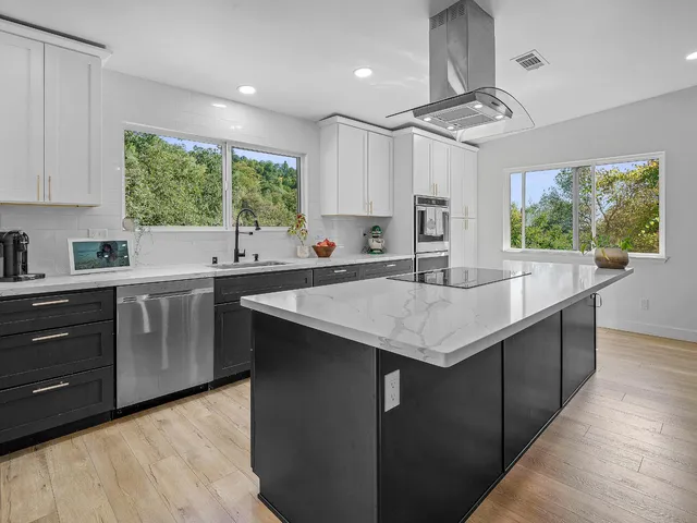 a kitchen with a stove a sink a center island and cabinets