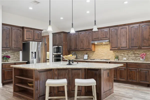 a kitchen with stainless steel appliances granite countertop a table chairs sink refrigerator and microwave