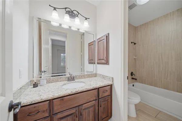 a bathroom with a granite countertop sink a toilet and a large mirror