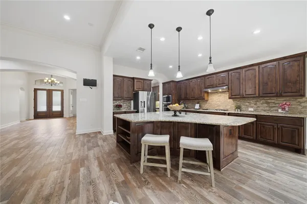 a kitchen with stainless steel appliances granite countertop a table chairs sink refrigerator and cabinets