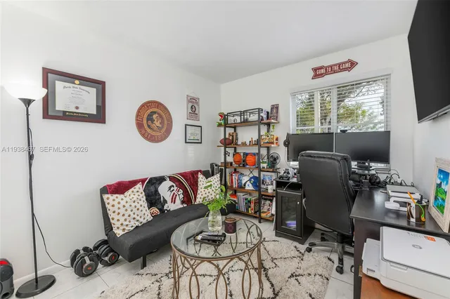 a work room with furniture a flat screen tv and a window