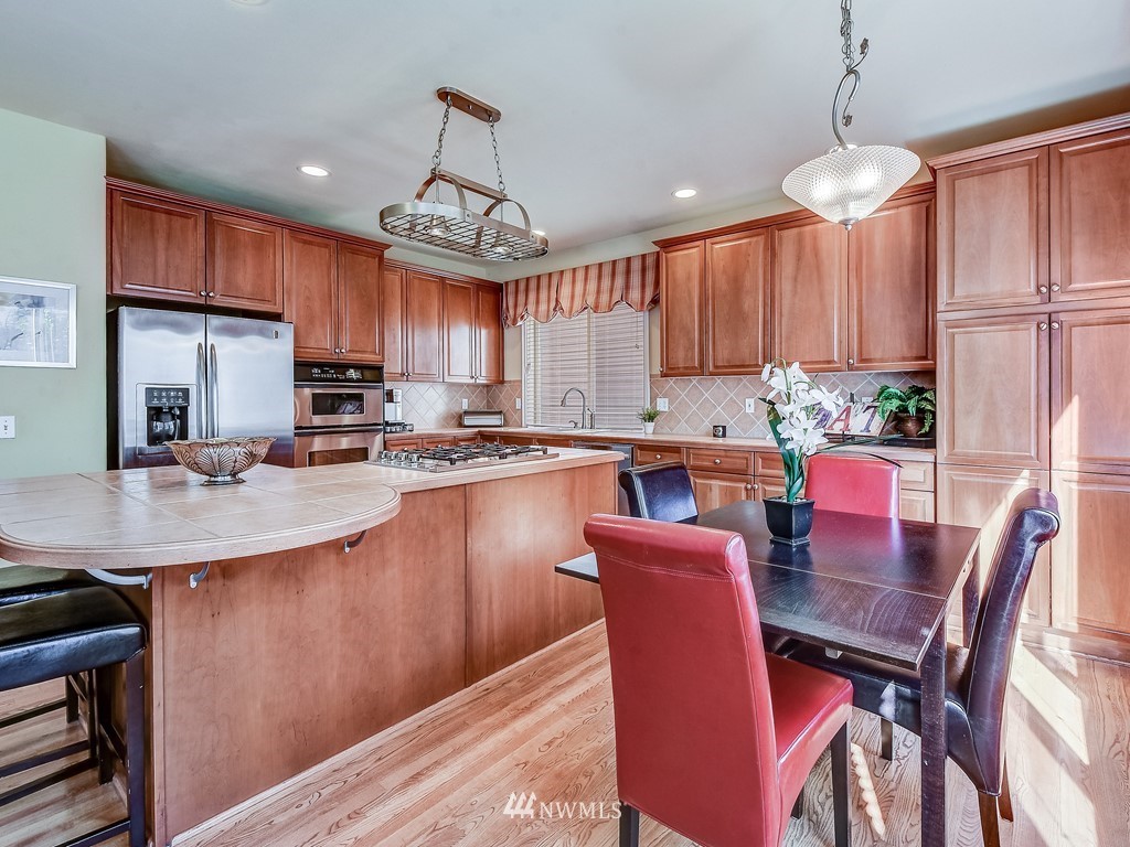 17070 Parkside Way Southeast Renton, WA 98058 - Photo 11 of 25 a kitchen with granite countertop a table chairs a sink dishwasher a dining table and chairs with wooden floor