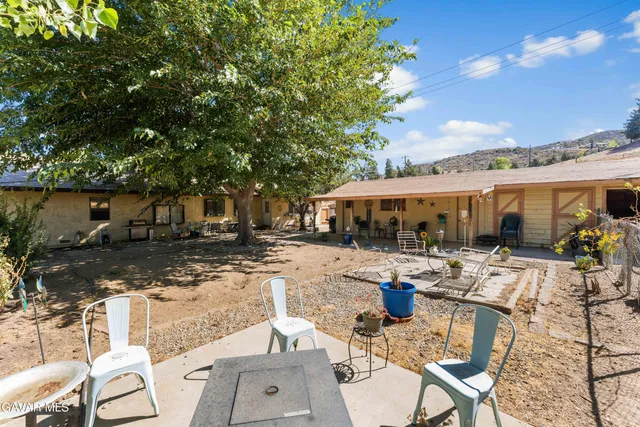 a view of a patio with table and chairs potted plants and large tree