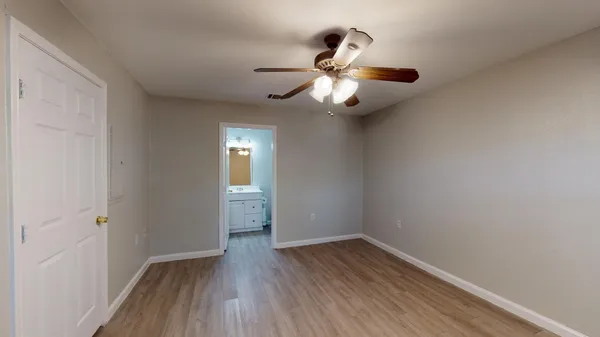 an empty room with wooden floor fan and windows