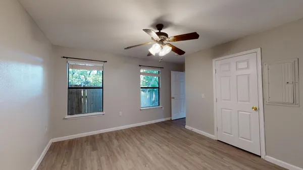 a view of empty room with wooden floor and fan