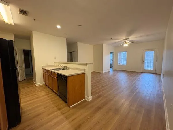a open kitchen with stainless steel appliances granite countertop a stove top oven and a refrigerator with wooden floor