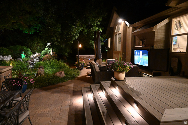 314 Brown Farm Lane Draper, UT 84020 - Photo 50 of 57 Expansive outdoor living area featuring a multi-level deck with integrated stair lighting, a stone-finish patio, a built-in outdoor television, and a lush landscaped garden with a water feature