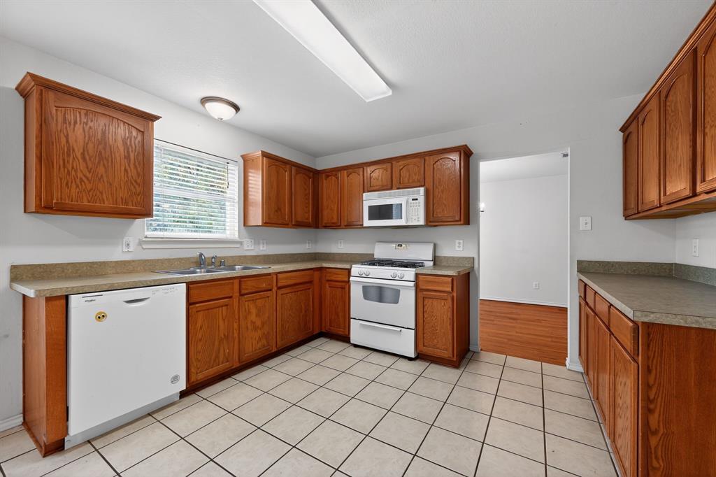 8618 Scooner Street Rowlett, TX 75089 - Photo 19 of 30 a kitchen with stainless steel appliances granite countertop a stove sink and cabinets
