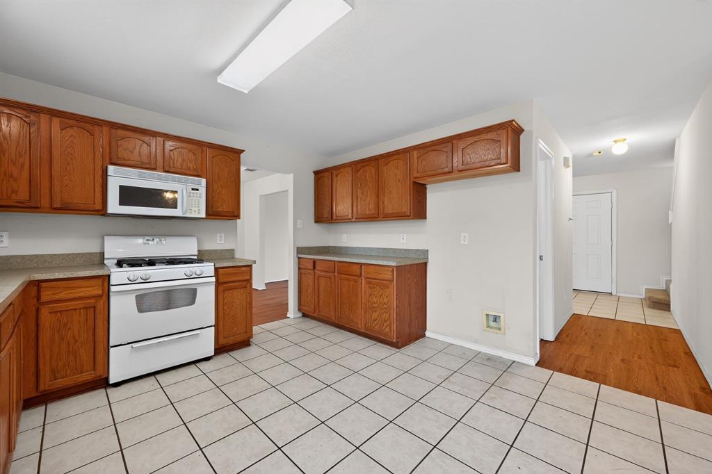 8618 Scooner Street Rowlett, TX 75089 - Photo 21 of 30 a kitchen with stainless steel appliances granite countertop a stove a sink and a microwave