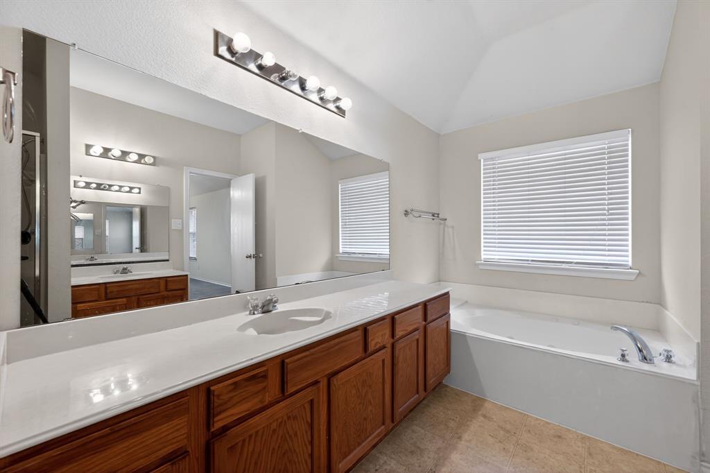 8618 Scooner Street Rowlett, TX 75089 - Photo 27 of 30 a bathroom with a tub a double vanity sink and mirror