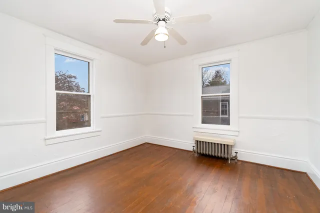 an empty room with wooden floor and ceiling fan