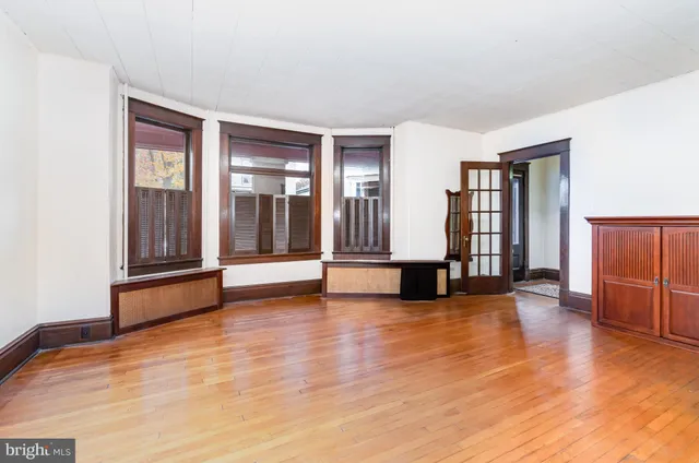 a view of empty room with wooden floor and seating