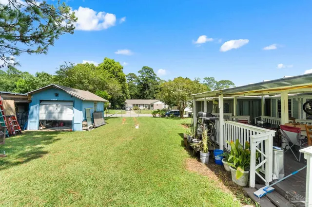 a view of a house with a yard porch and wooden fence