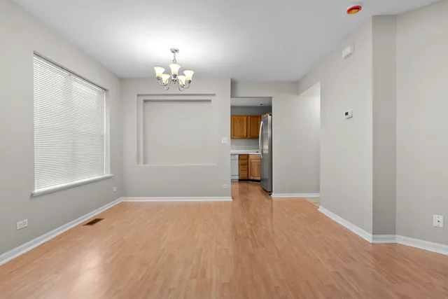 an empty room with wooden floor chandelier and windows