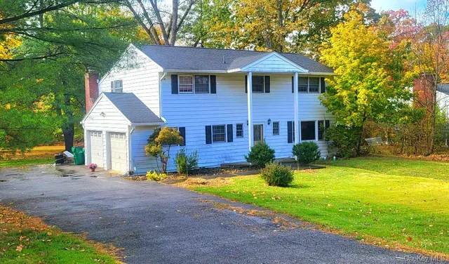a front view of house with yard and trees in the background