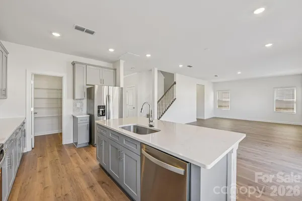 a kitchen with stainless steel appliances a sink and wooden floor