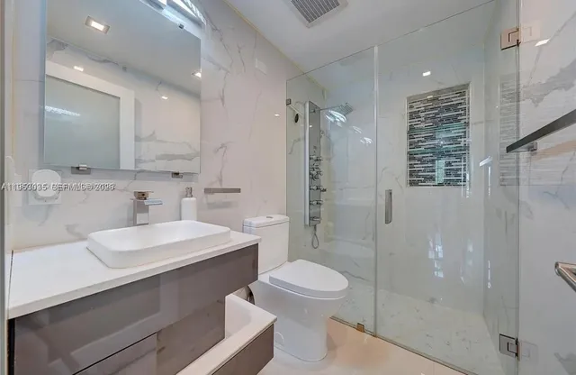 a bathroom with a sink a toilet a mirror and shower