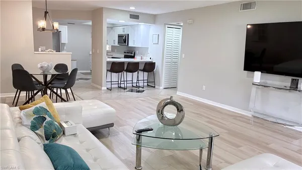 a living room with furniture a flat screen tv and kitchen view
