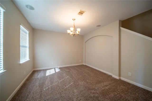 an empty room with windows and chandelier