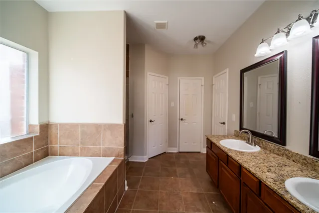 a bathroom with a granite countertop tub sink and mirror