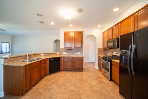 a large kitchen with stainless steel appliances granite countertop a sink and cabinets