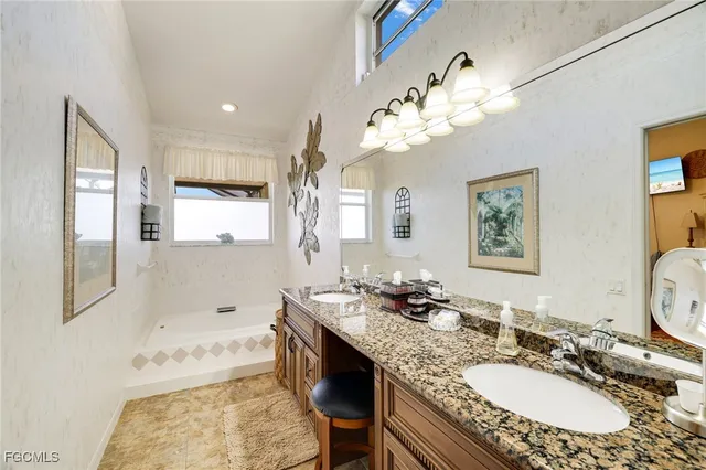 a bathroom with a granite countertop double vanity sink a mirror and a bathtub