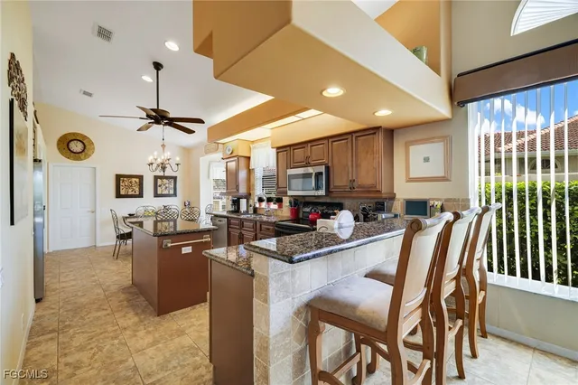 a kitchen with stainless steel appliances kitchen island granite countertop a table chairs and a refrigerator