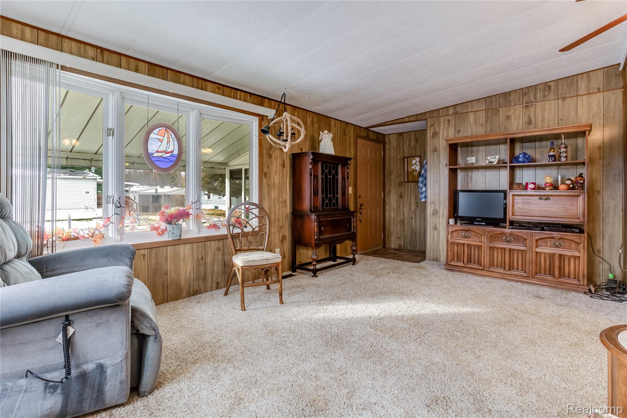 3333 Ravenswood Road Marysville, MI 48040 - Photo 11 of 25 Carpeted living room with wooden walls and lofted ceiling