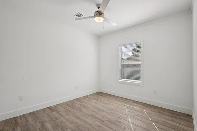 an empty room with a window and ceiling fan