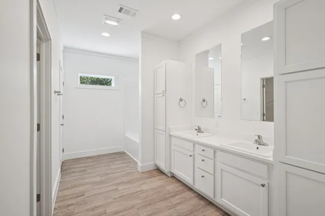 a spacious bathroom with a double vanity sink a large mirror and shower