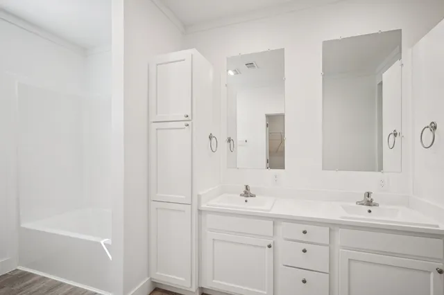 a bathroom with a double vanity sink a mirror and a bathtub