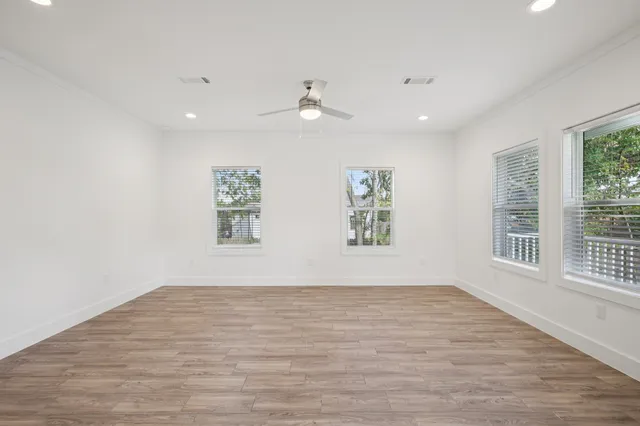 an empty room with wooden floor and windows