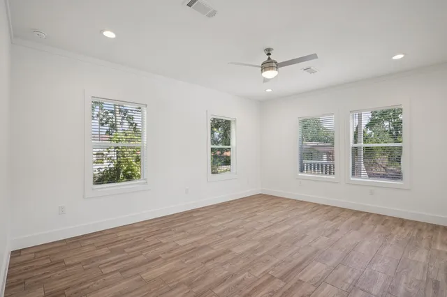 a view of an empty room with wooden floor and a window