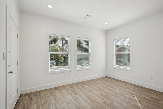 an empty room with wooden floor and windows