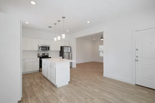 a view of kitchen with kitchen island a refrigerator and a stove top oven