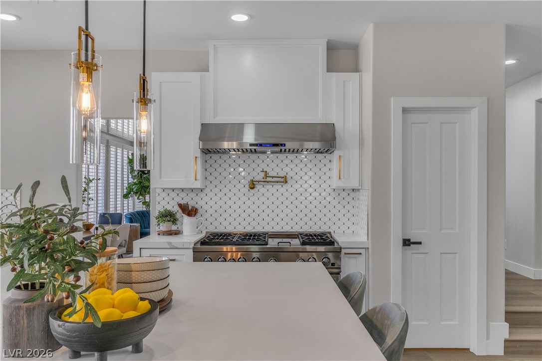 8848 Rainbow Ridge Drive Las Vegas, NV 89117 - Photo 16 of 43 A well-appointed culinary space featuring a large island, premium range, and striking tile backsplash.