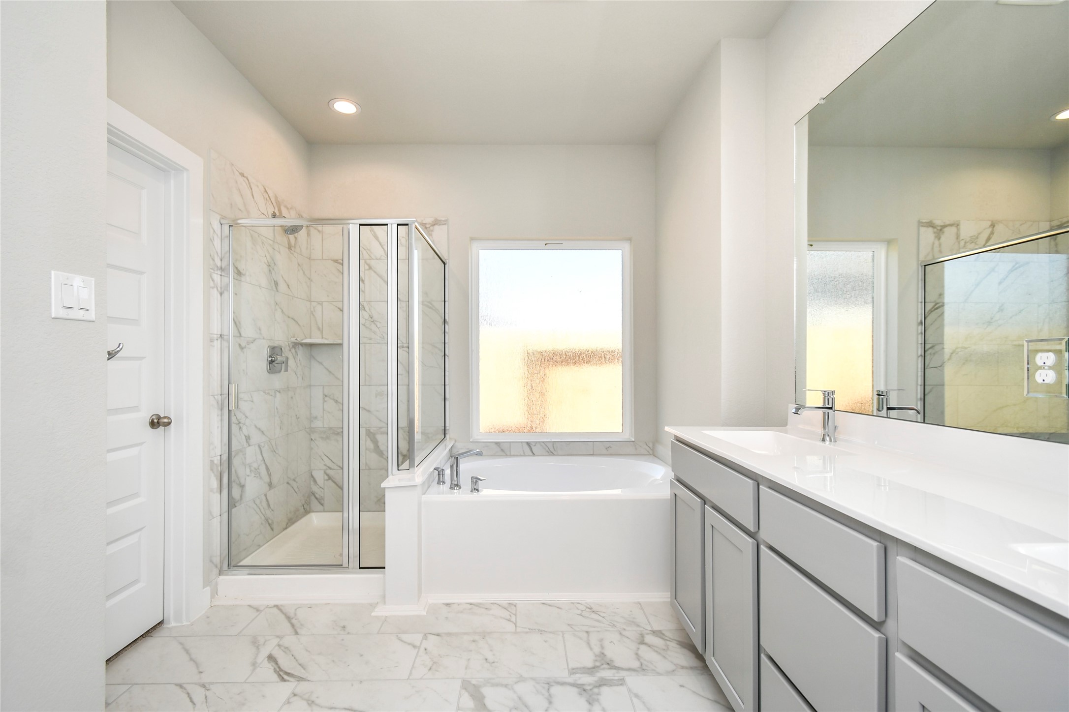 15115 Statice Trail Houston, TX 77044 - Photo 18 of 25 Experience a spa-like escape right in the heart of your primary bathroom. The
expansive walk-in shower, surrounded by tile, and the distinctive garden tub
with unique accents elevate your daily routine. The sophisticated vanity,
featuring double sinks, light-colored countertops, contemporary hardware, and
bright recessed lighting, adds both style and functionality to the space. Sample photo of completed home with similar floor plan. Actual colors and selections may vary.