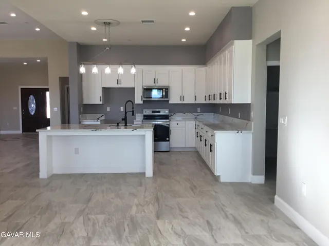 a view of a kitchen with kitchen island a sink stainless steel appliances and cabinets