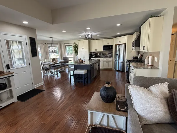 a living room with furniture a wooden floor and a view of kitchen