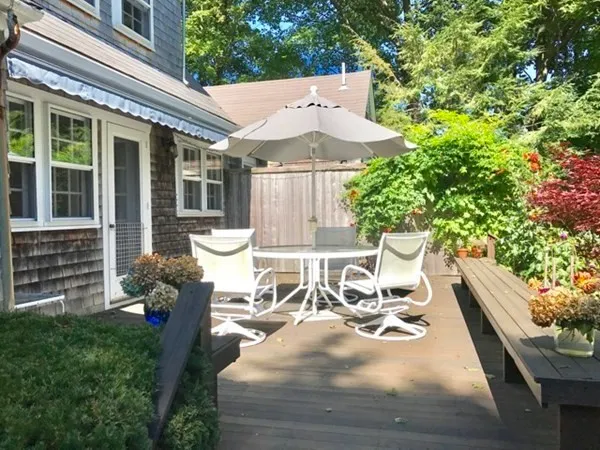 a view of a patio with table and chairs potted plants and large tree